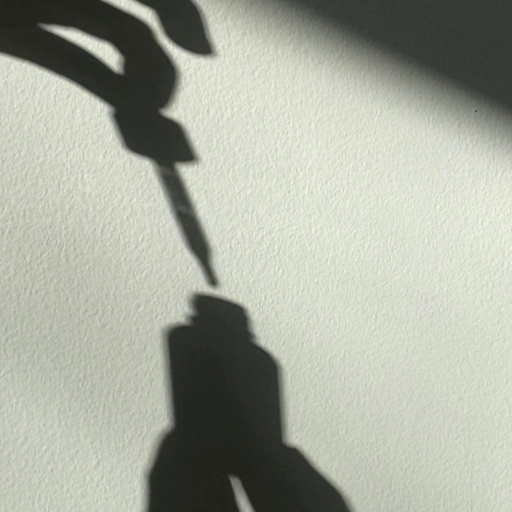 Shadow of a hand holding a pen on a light background
