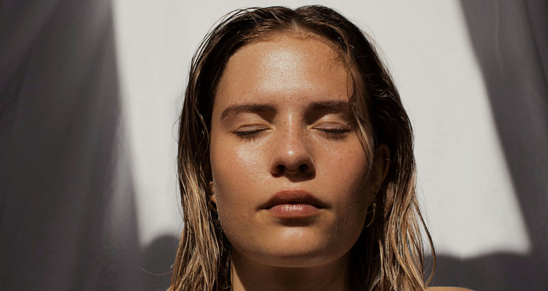 Woman with closed eyes against a white and gray background